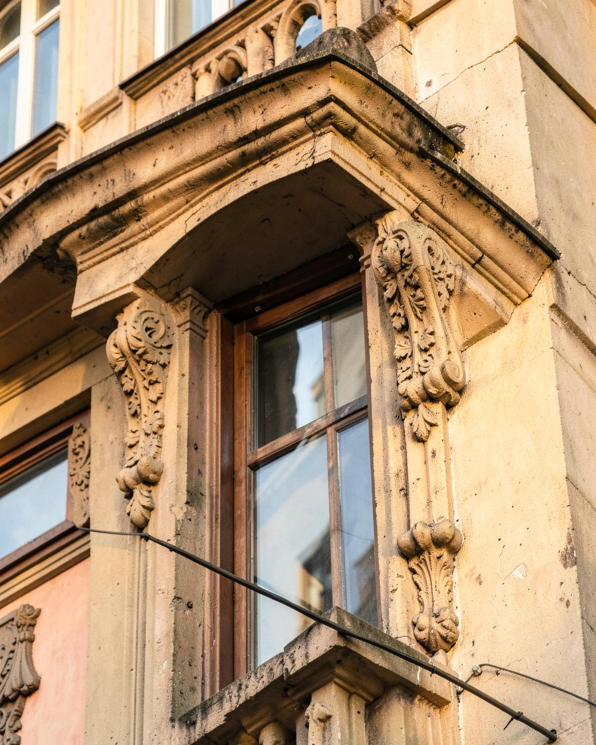Sandsteinerne Fensterbekrönung mit Ornamentkonsolen im Detail